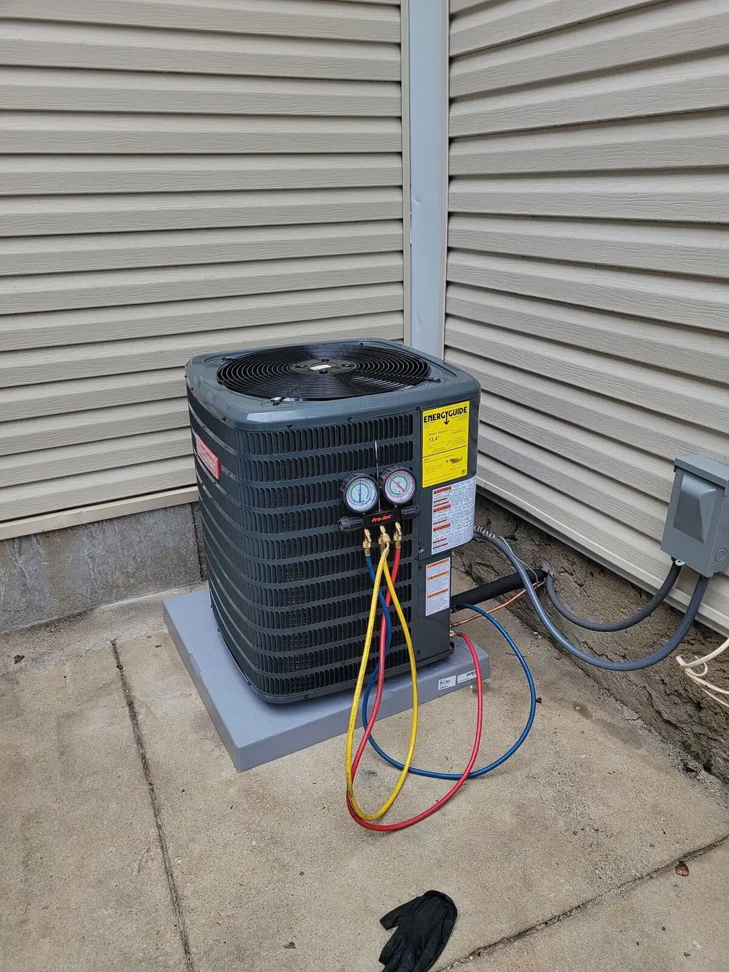 An outdoor AC condenser with refrigerant gauges connected during a service visit