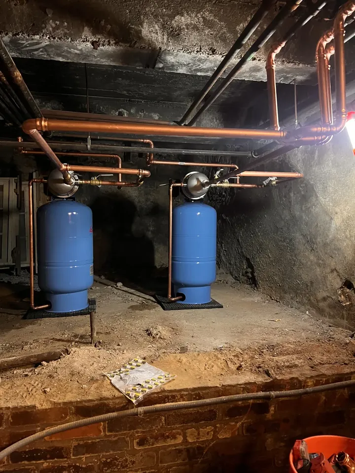 Copper repipe at a water service entry with two blue expansion tanks and new valves