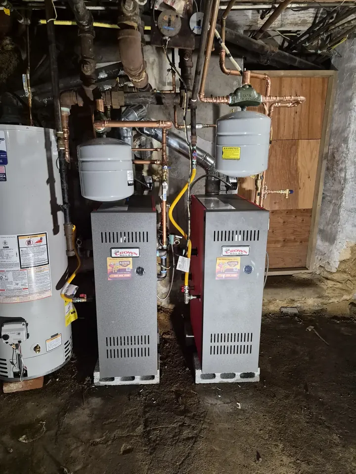 Finished twin boiler installation seen from the side, showing venting and gas piping