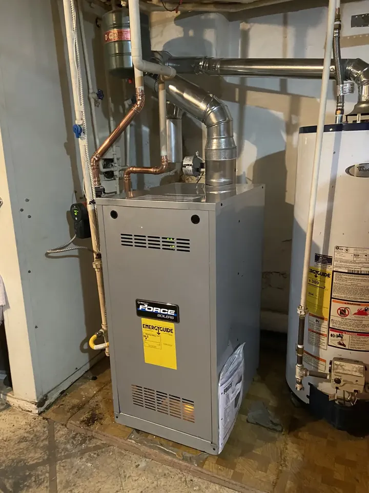 New gas furnace with sealed supply and return ductwork beside a water heater
