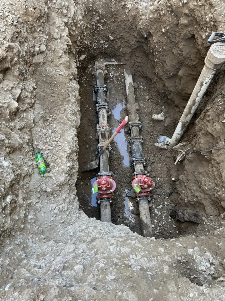 Several pipes exposed at a water service connection point in an excavation
